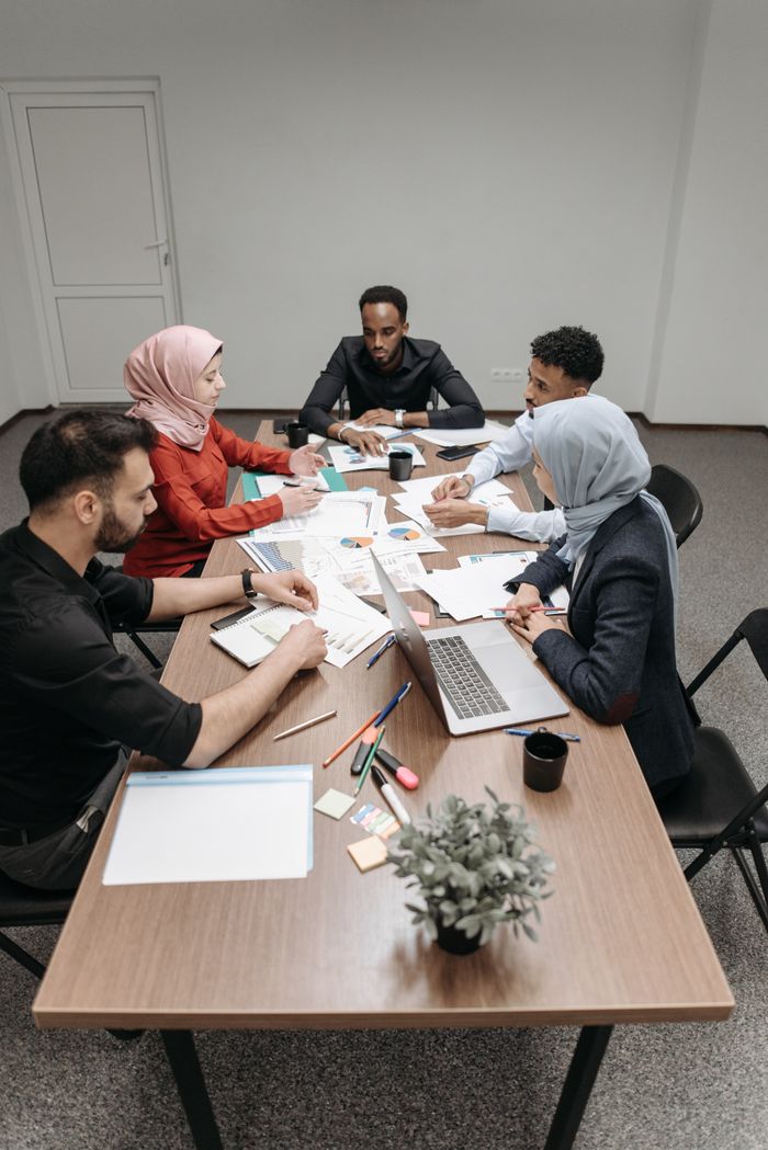 Services A multicultural team engaged in a collaborative meeting at a modern office setting with laptops and paperwork.