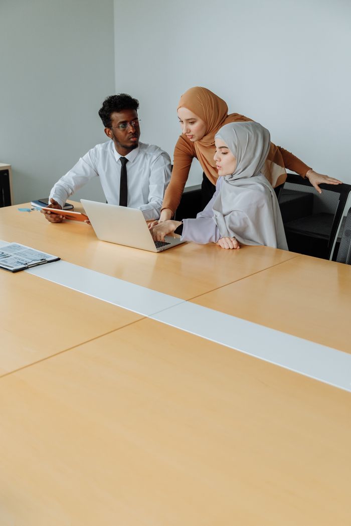 Services Colleagues from different backgrounds collaborating on a laptop in a modern office setting.